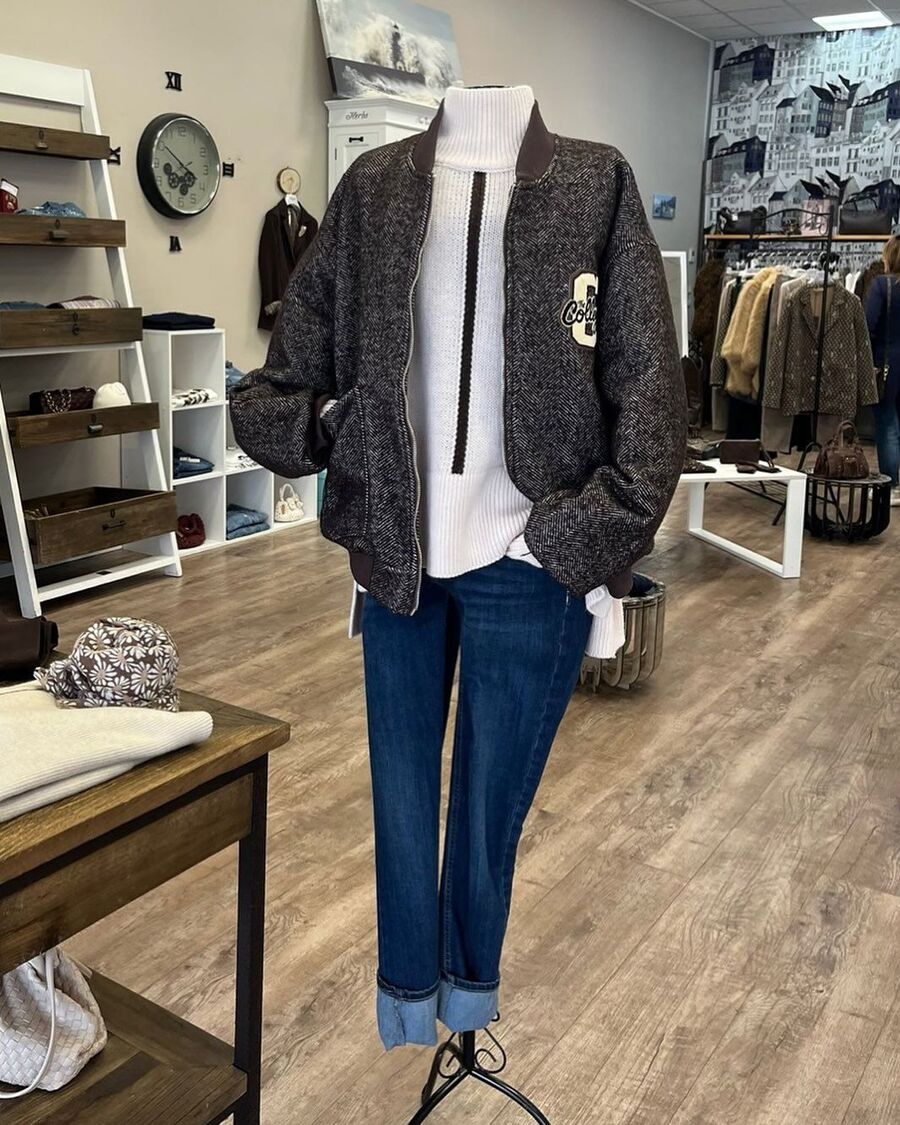Outfit con bomber, camicia bianca e jeans esposto in negozio